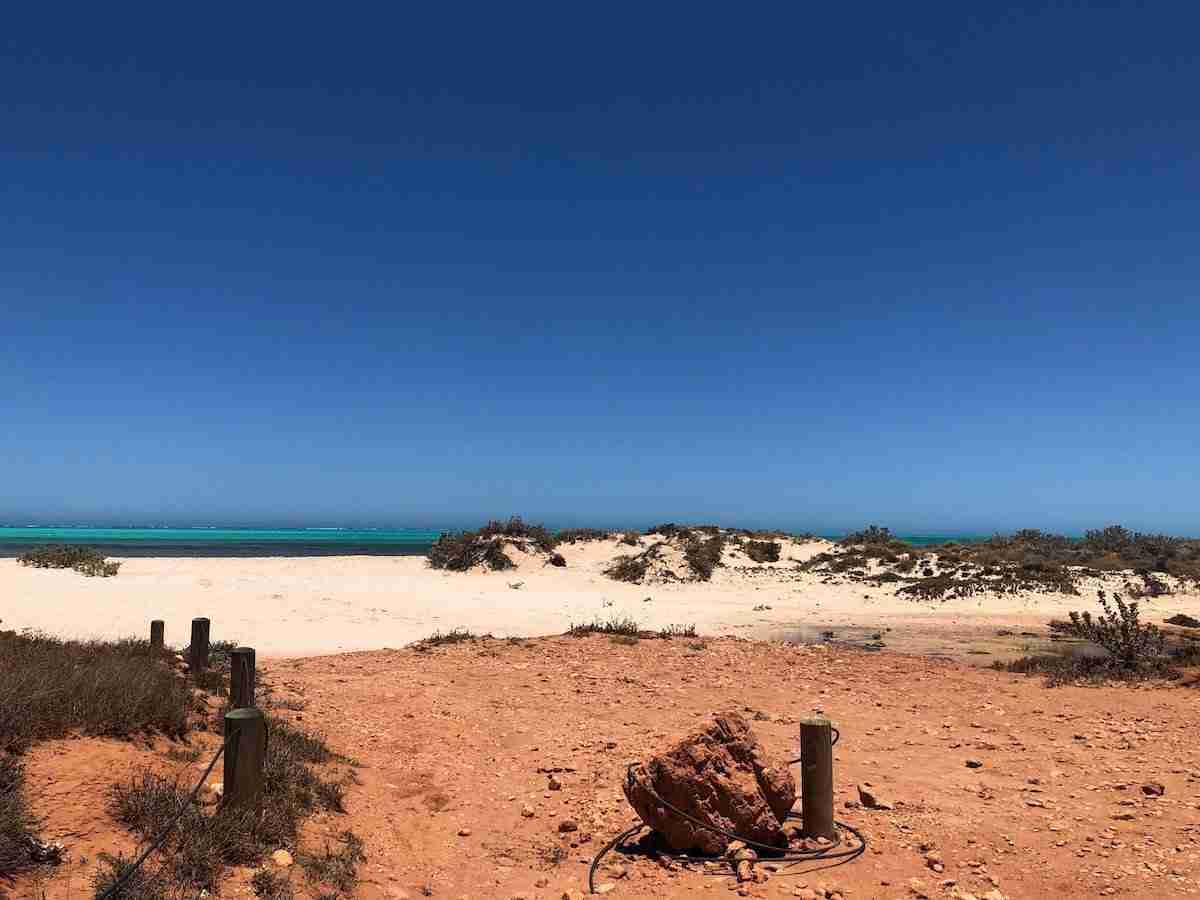 Parc National de Cape Range-vue sur la mer turquoise avec terre rouge au premier plan et sable blanc. Voyage en Australie de l'Ouest