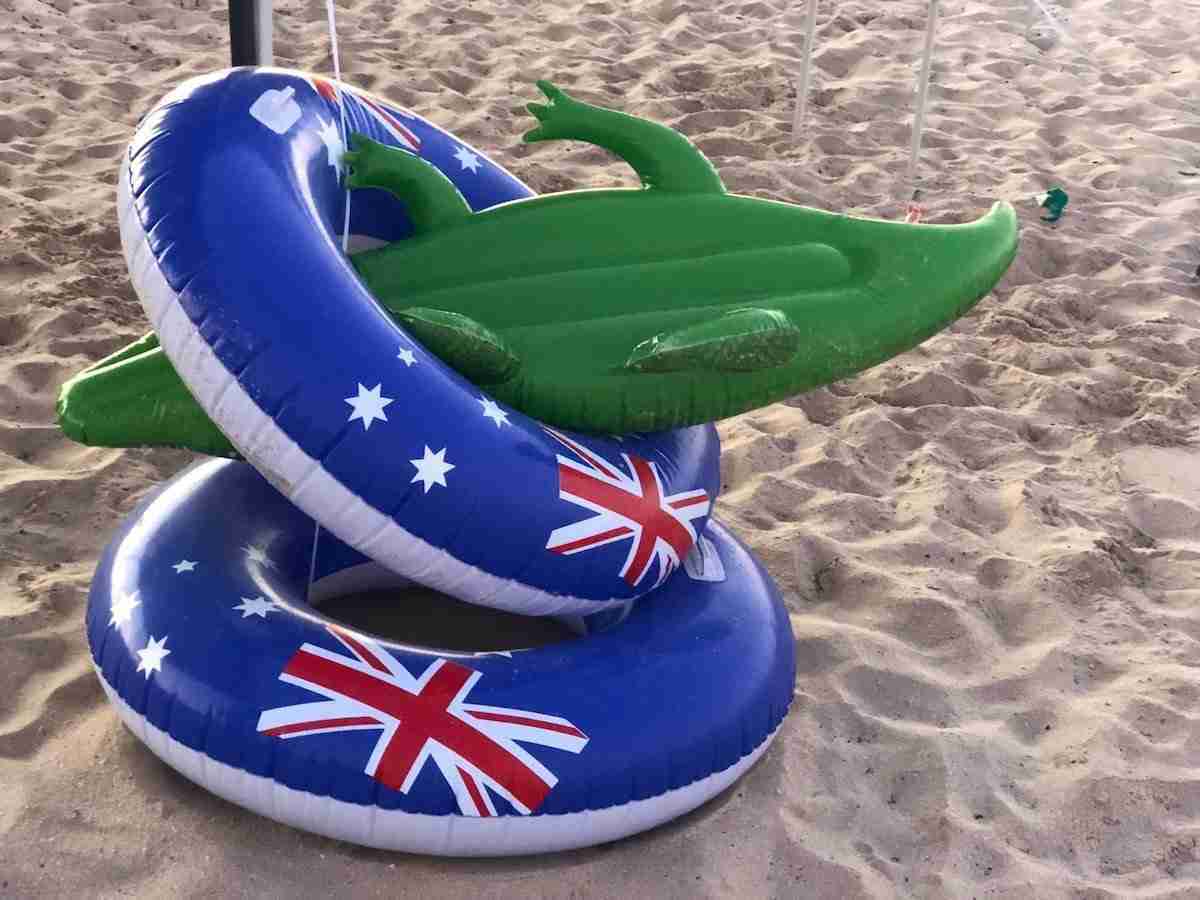 3 bouées sur la plage. Une en forme de crocodile et deux décorées du drapeau australien